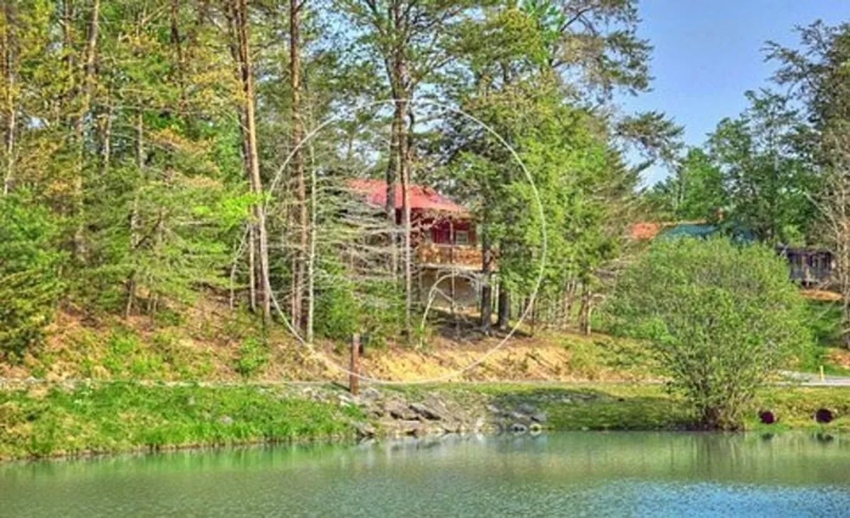A picturesque cabin nestled in the woods beside a calm lake, surrounded by trees and natural beauty. The tranquil setting is ideal for exploring, enjoying nature, or savoring quiet moments together.